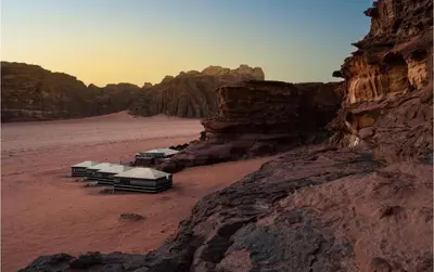 a group of beds in the desert near a mountain at Milky Way Bedouin Camp in Wadi Rum