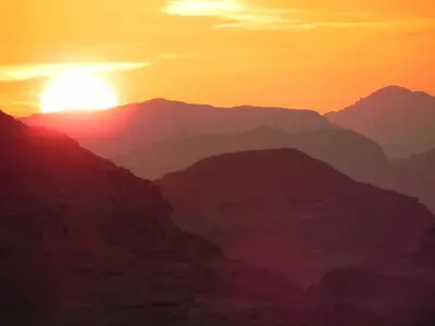 a sunset over the mountains in the desert at Bedouin Traditions Camp in Wadi Rum