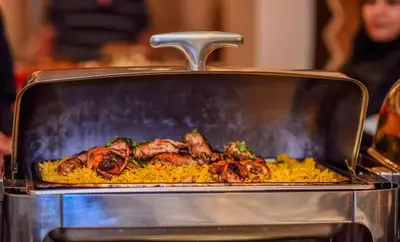 a grill with meat on top of yellow rice at La Maison Hotel in Wadi Musa