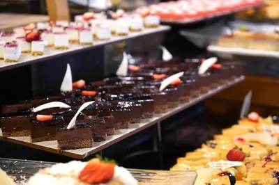 a display of chocolate cakes and other desserts on shelves at MENA Tyche Hotel Amman in Amman