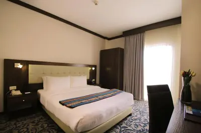 a hotel room with a large bed and a window at MENA Tyche Hotel Amman in Amman