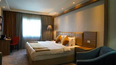 a hotel room with a bed and a chair at MENA Tyche Hotel Amman in Amman