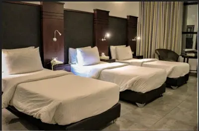 a hotel room with three beds with white sheets at Torino Hotel Amman in Amman