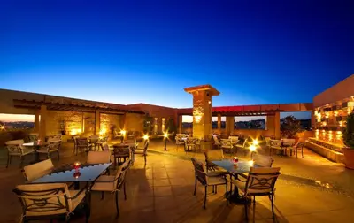a patio with tables and chairs at night at Sadeen Amman Hotel in Amman