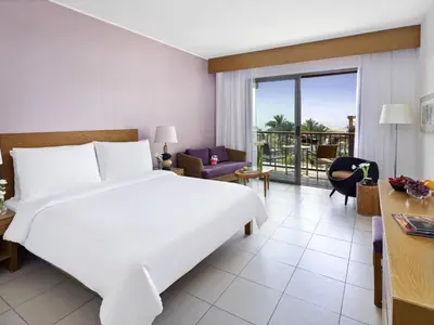a hotel room with a bed and a balcony at Mövenpick Resort & Spa Tala Bay Aqaba in Aqaba