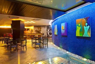 a restaurant with tables and chairs against a blue wall at Dead Sea Spa Hotel in Sowayma