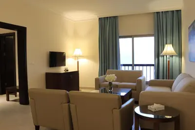 a living room with a couch and chairs and a tv at Dead Sea Spa Hotel in Sowayma