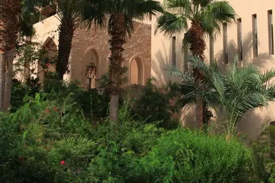 a building with palm trees and plants in front of it at Ma'in Hot Springs in Sowayma
