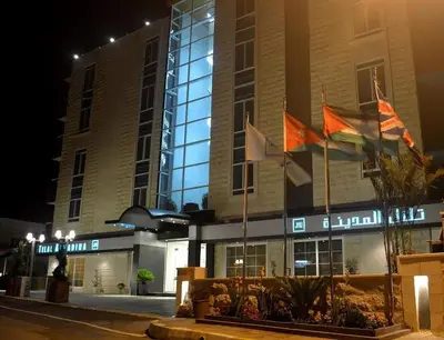 a building with flags in front of it at night at Tilal Almadina Hotel & Suites in Amman