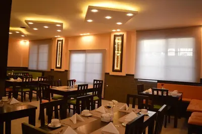 a restaurant with tables and chairs and a large window at Tilal Almadina Hotel & Suites in Amman