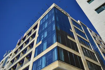 a tall glass building with a blue sky in the background at Sulaf Luxury Hotel in Amman