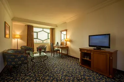 a hotel room with a television and a living room at Bristol Hotel in Amman