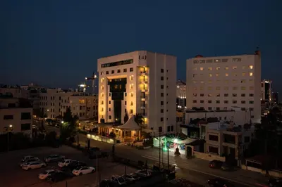 a city at night with cars parked in a parking lot at Bristol Hotel in Amman
