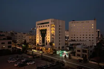 a city at night with cars parked in a parking lot at Bristol Hotel in Amman
