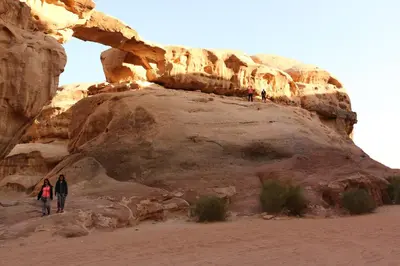 people walking on a rock formation in the desert at Bedouin life Camp in Wadi Rum