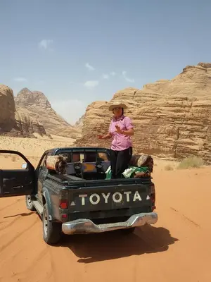 a woman sitting on the back of a truck in the desert at Bedouin life Camp in Wadi Rum