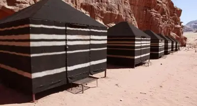 a row of black and white tents in the desert at Jordan Tracks Bedouin Camp in Wadi Rum