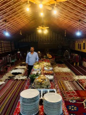 a man standing in a room with a table full of plates at Wadi Rum Starlight Camp in Wadi Rum