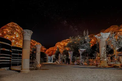 a building with columns and trees at night at Little Petra Bedouin Camp in Al Ḩayy