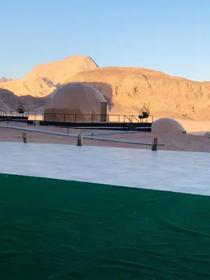 two domes in the middle of a desert with a mountain at Hasan Zawaideh luxury camp 2 in Wadi Rum