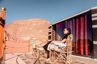 a woman sitting in a chair on a balcony at Wadi Rum Sky Tours & Camp in Wadi Rum