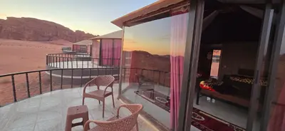 a balcony with two chairs and a view of the desert at Wadi Rum Candles Camp in Wadi Rum