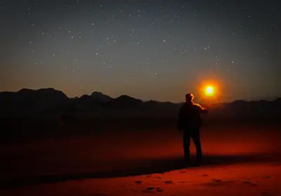 a man holding a light in the middle of the desert at Wadi Rum Candles Camp in Wadi Rum
