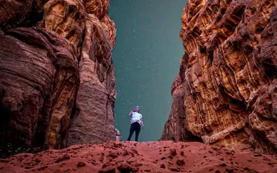 a person standing on top of a rock formation at Wadi Rum Candles Camp in Wadi Rum