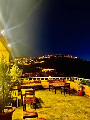 a balcony with tables and chairs and a view of a city at Esperanza Petra in Wadi Musa