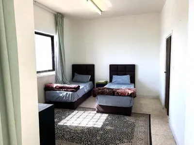 a room with two beds and a window at Al Qatal Building in Al Qasţal