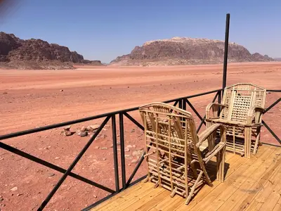 two chairs sitting on a deck in the desert at Wadi Rum Quiet Village Camp in Wadi Rum