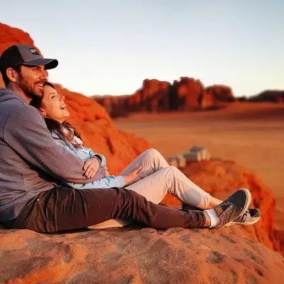a man and a woman sitting on a rock at Wadi Rum Dream Camp in Wadi Rum