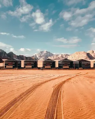 a row of buildings in the desert with mountains in the background at Wadi Rum Dream Camp in Wadi Rum