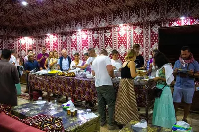 a group of people standing around a table with food at Wadi Rum Dream Camp in Wadi Rum
