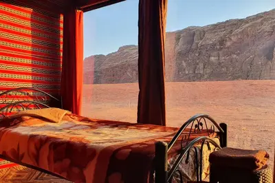 a bed in a room with a view of the desert at Welcome to Wadi Rum Camp in Wadi Rum
