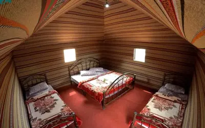 a small room with two beds in a wooden room at Rumshines Camp in Wadi Rum