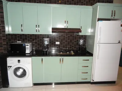 a kitchen with blue cabinets and a white refrigerator at Diyarkom Apartment in Amman