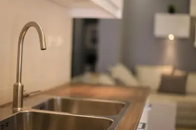 a stainless steel sink in a kitchen with a couch at Elite Residency in Amman