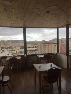 a restaurant with tables and chairs and large windows at Petra Cabin Inn Hostel&Resturant in Wadi Musa
