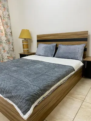 a bedroom with a large bed with blue pillows at Sami Apartments in Amman