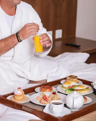 a man sitting in bed with a tray of food at Gerasa Hotel in Amman