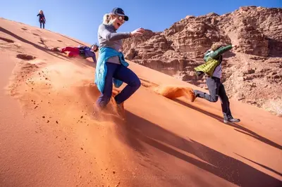 two people and a dog running in the desert at Wild of Wadi Rum in Wadi Rum