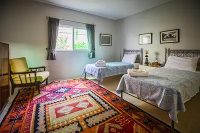 a bedroom with two beds and a rug at Beit Al Baraka in Um Qeis
