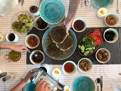 a table topped with plates of food with people serving food at Beit Al Baraka in Um Qeis