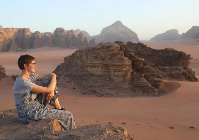 a man sitting on a rock in the desert at Rum Planet Camp in Wadi Rum