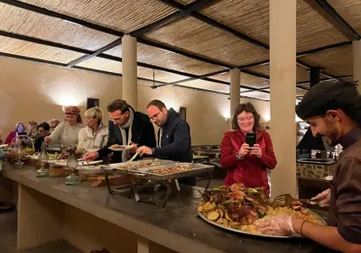 a group of people standing around a table with food at Rum Planet Camp in Wadi Rum