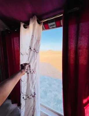 a person is opening a curtain on a train at Red Mountain Camp in Wadi Rum
