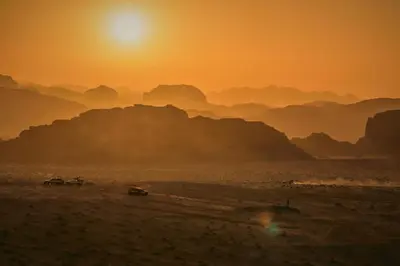 a sunset in the desert with mountains in the background at Red Mountain Camp in Wadi Rum