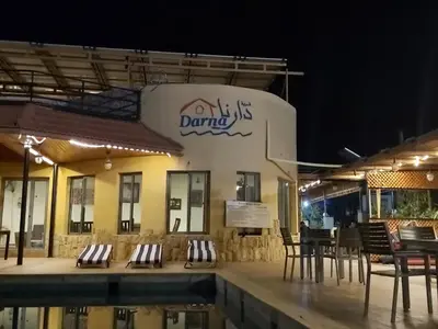 a restaurant with chairs and a swimming pool at night at Darna Divers Village in Aqaba