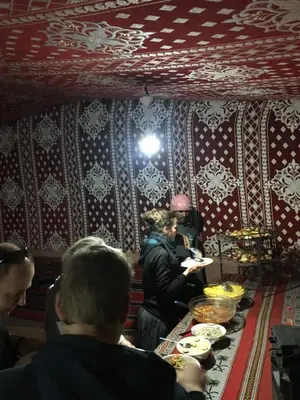 a group of people sitting around a table with food at Wadi Rum Lawrence Camp in Wadi Rum